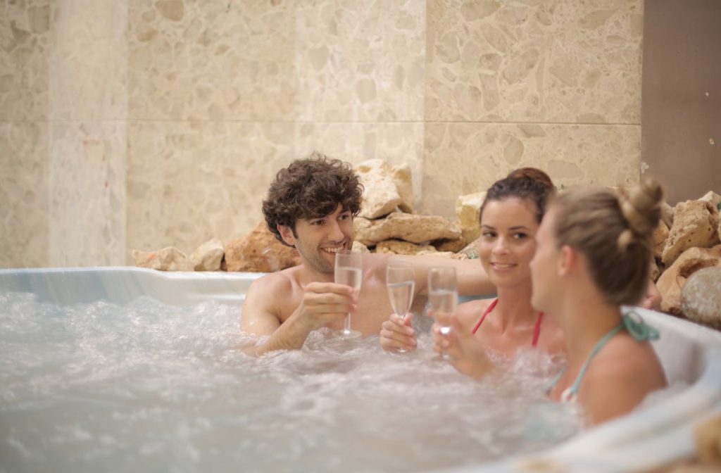 Offerings Group of friends toasting with drinks in a hot tub, enjoying relaxation and togetherness indoors.