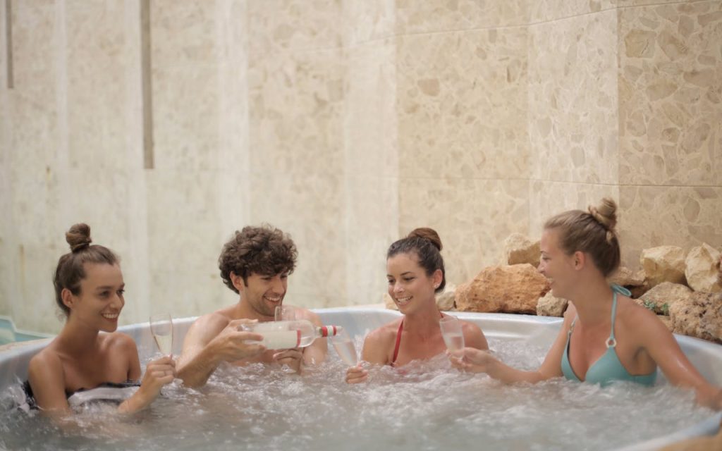 Offerings Friends having fun and relaxing together in a jacuzzi with drinks indoors.
