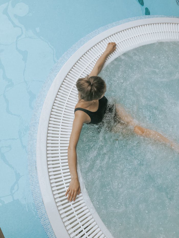 Home A person enjoys a serene soak in a stylish circular jacuzzi spa, ideal for relaxation.